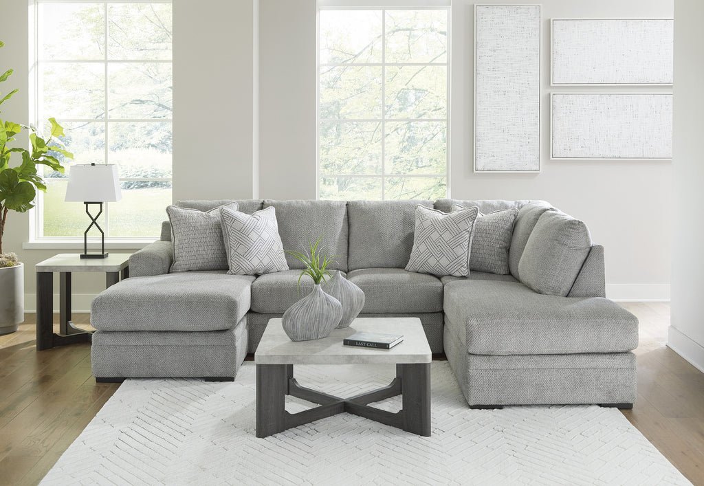 Grey plush U-shaped sectional sofa with chaise, Ashley Casselbury 2-piece design in cement fabric, shown in a living room setting.