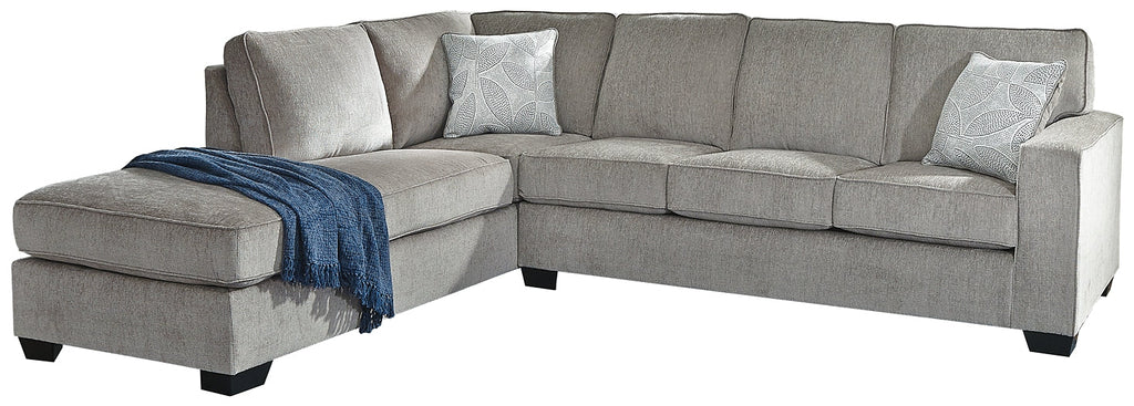 Grey L-shaped sleeper sectional by Ashley with plush fabric and modern design, shown in a stylish studio setting.