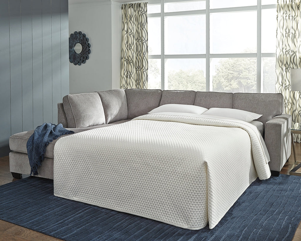 Grey Ashley L-shaped sleeper sectional sofa in a modern studio setting, featuring plush cushions and a spacious design.