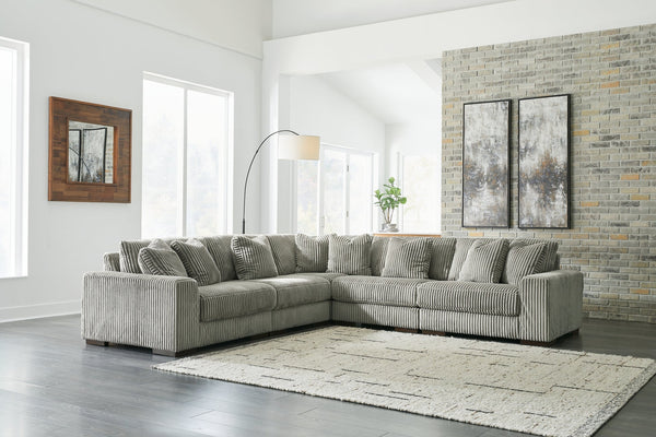 Green corduroy L-shaped sectional sofa by Ashley, shown in a modern studio setting with plush cushions and a spacious design.