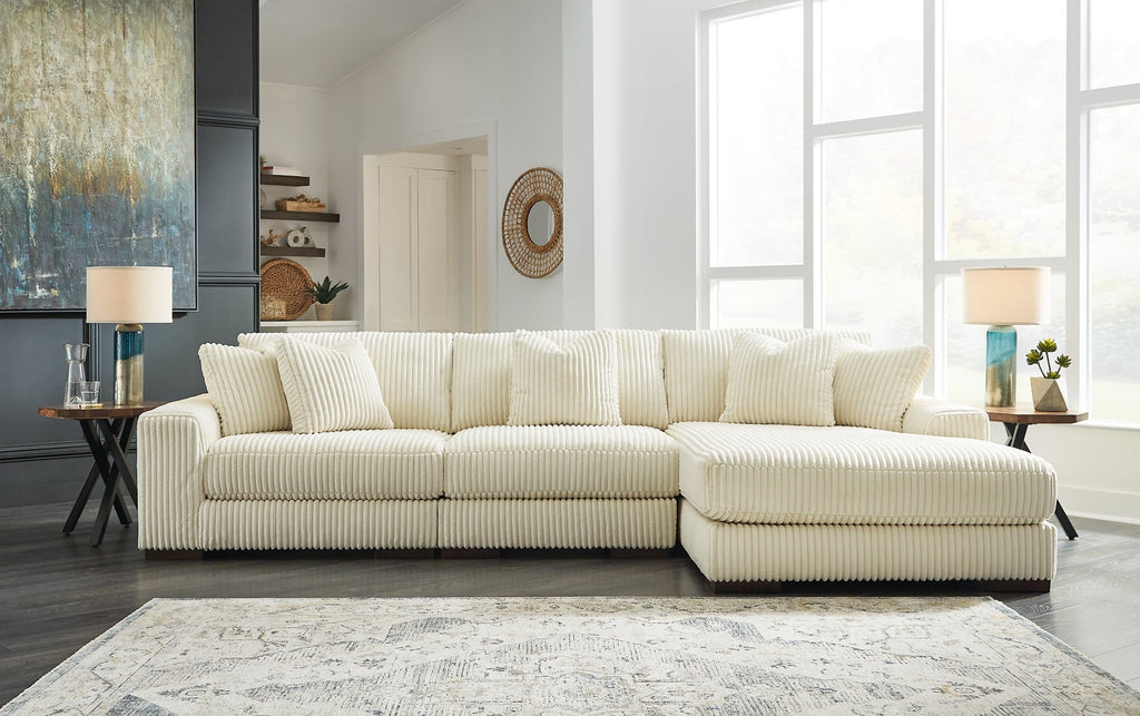 Ivory corduroy sofa chaise by Ashley, featuring plush cushioning and modern design, shown in a stylish studio setting.