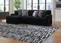 Black corduroy sofa chaise from Signature Design by Ashley® with plush cushions and modern design in a studio setting.