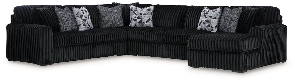 Black corduroy U-shaped sectional sofa by Ashley, featuring plush cushions and a modern sectional design, photographed in a studio setting.