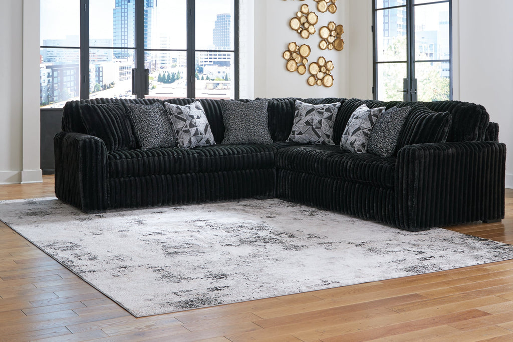 Black corduroy Ashley L-shaped sectional sofa in a modern living room setting with plush cushions.