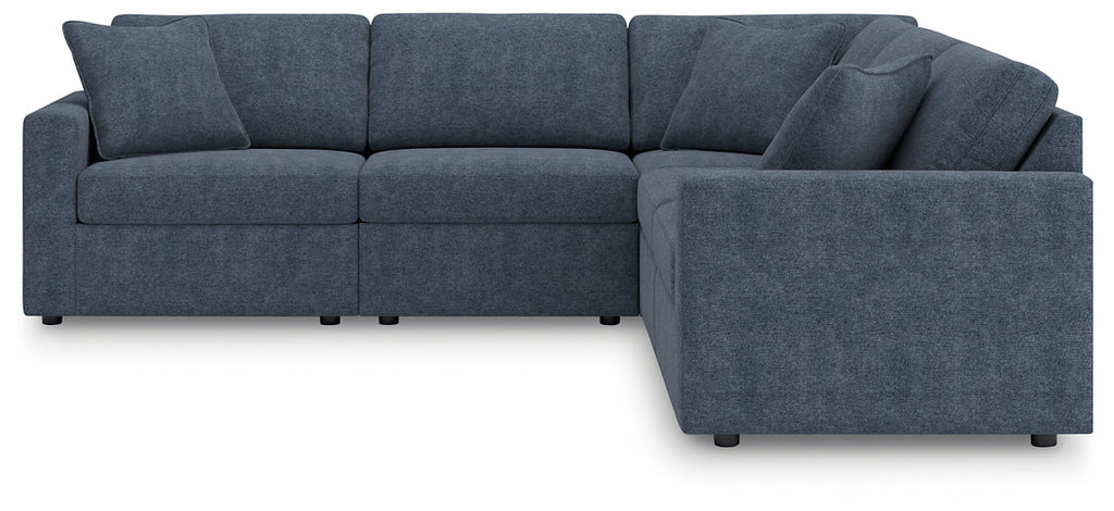 Blue Ashley modular L-shaped sectional sofa in a modern studio setting, featuring plush cushions and sleek design.