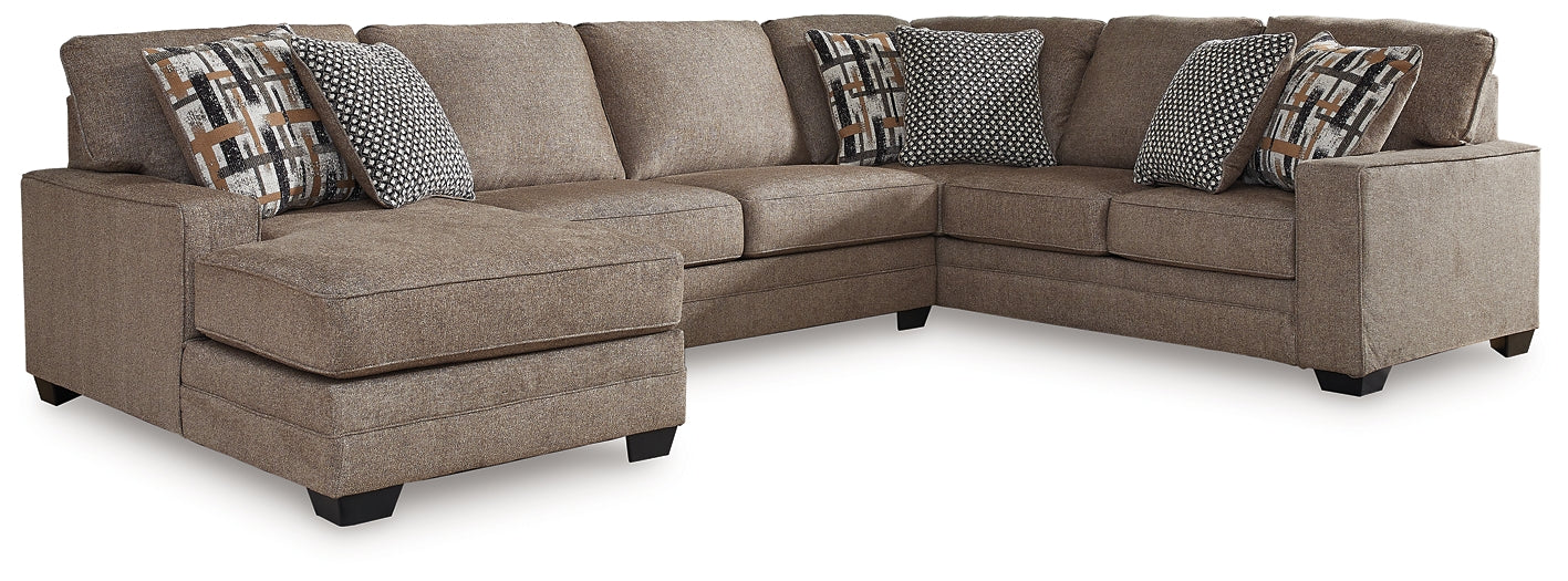 Brown U-shaped sectional sofa by Ashley, showcasing plush upholstery and spacious seating in a modern living room setting.