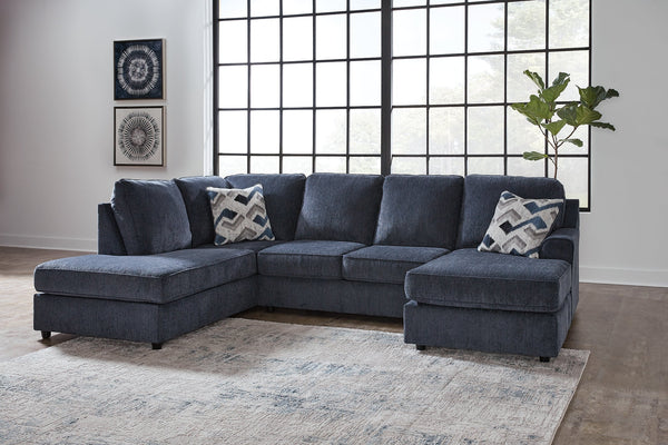 Blue U-shaped sectional sofa by Ashley with plush cushions and modern design, shown in a stylish living room setting.