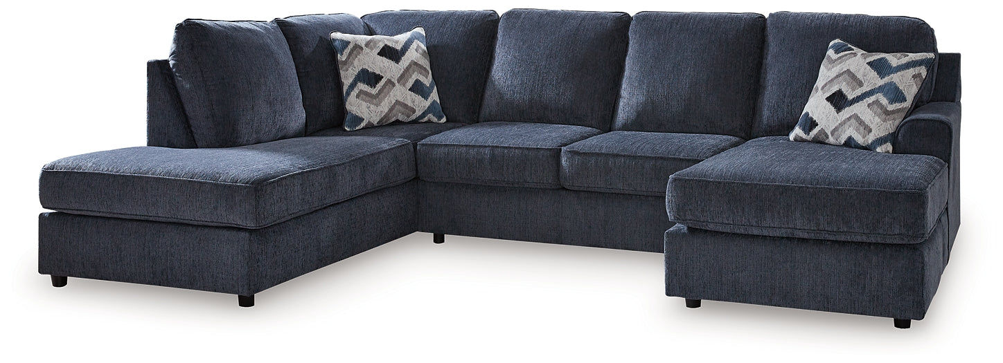 Blue U-shaped sectional sofa by Ashley with plush cushions and modern design, shown in a stylish living room setting.