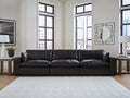 Three-piece black genuine leather sectional sofa by Ashley, shown in a modern studio setting with plush cushions and sleek design.