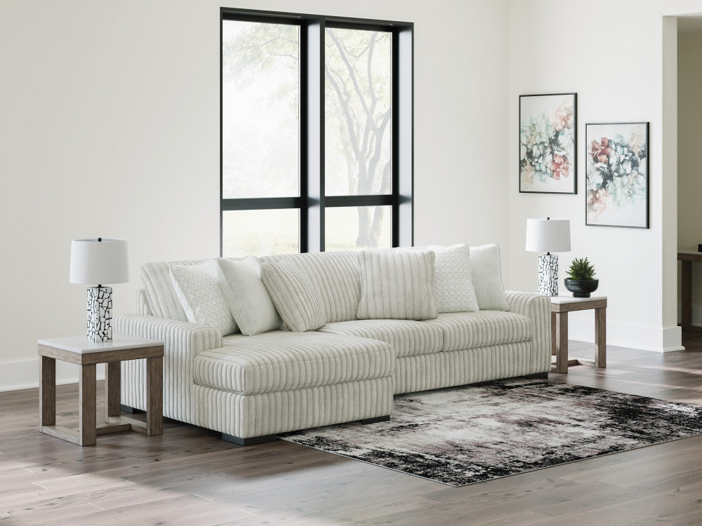 Light grey corduroy sofa chaise by Ashley with plush cushions and modern design, shown in a stylish studio setting.